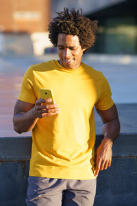 Black man consulting his smartphone while resting from his workout