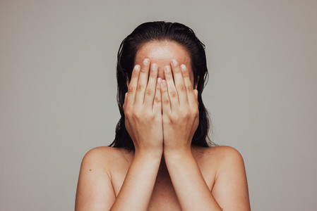 Close up of woman hiding her face with hands