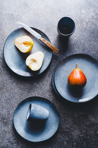 Blue food ceramic set with plates and pears over grey textured background  Minimalist style  top view