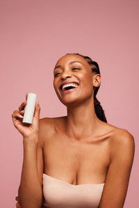 Woman holding a skincare product and smiling