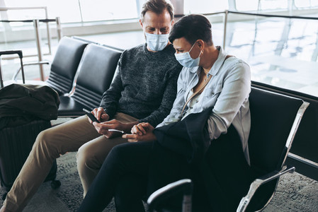 Couple waiting at airport checking flight information on phone