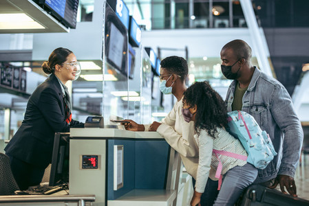 Ground staff assisting family at checkin counter during pandemic