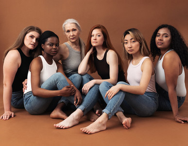 Diverse women in casuals sitting on brown background  Multi ethnic group of females looking at camera in studio