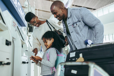 Tourist family doing self service check in for flight