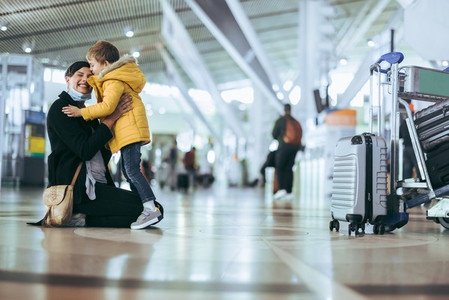 Woman arriving from trip meeting son at airport