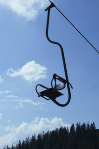 Empty ski lift chair against sunny blue sky