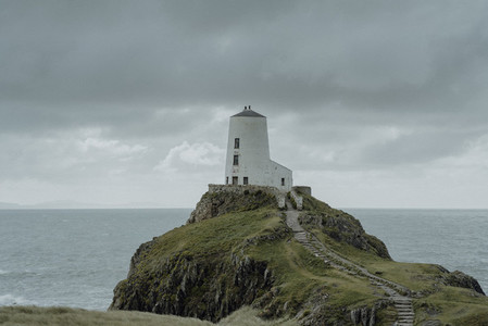 Lighthouse on ocean cliff under cloudy sky Wales
