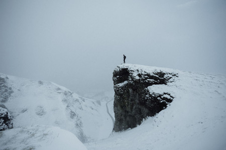 Hiker on remote snow covered cliff England