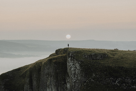 Hiker on cliff at sunrise England