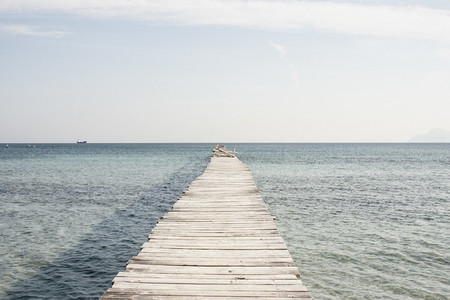 Wooden pier extending into sunny ocean Spain