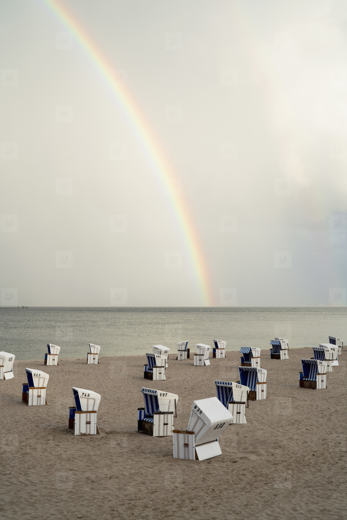 Rainbow over cabanas on tranquil ocean beach  Germany