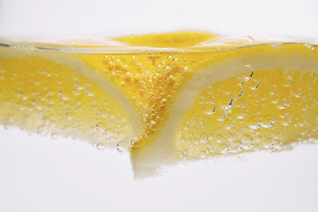 Extreme close up lemon wedge in sparkling water