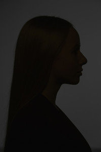 Dark silhouette young woman on black background