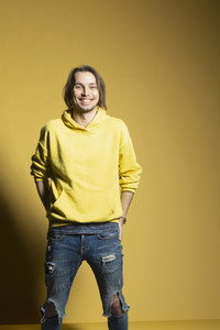 Portrait happy young man in sweatshirt and ripped jeans