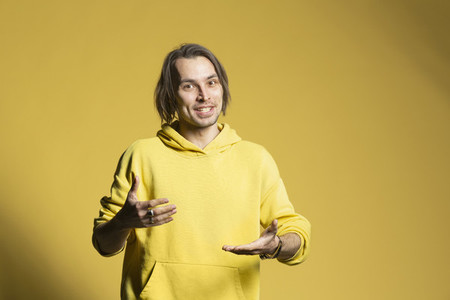 Portrait young man talking and gesturing on yellow background