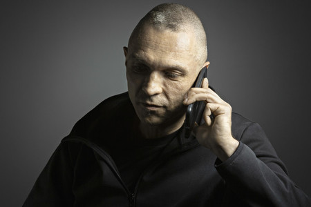 Mature man talking on smart phone against black background