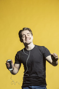 Carefree man with mp3 player listening and dancing to music
