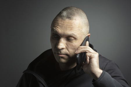 Mature man talking on smart phone against black background