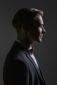 Profile portrait handsome young man in suit with bow tie