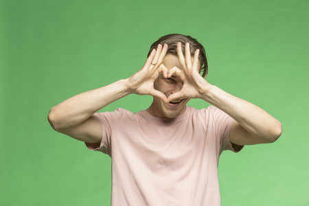 Portrait young man gesturing heart shape with hands