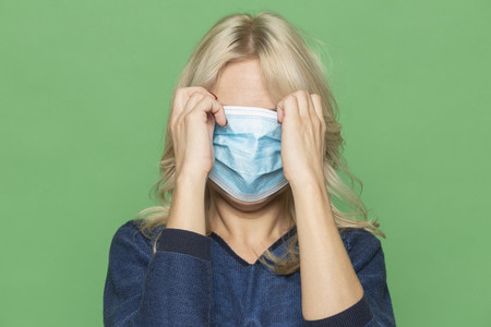 Studio portrait woman covering face with protective face mask
