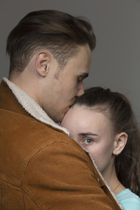 Portrait worried young woman in arms of boyfriend