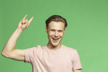 Portrait carefree young man gesturing horn sign