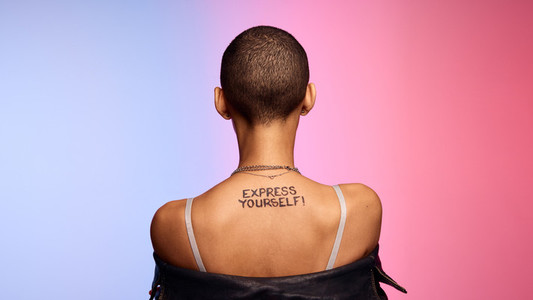 Androgynous female with express yourself written on her back