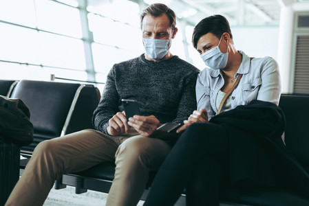 Couple using phone while waiting for their flight