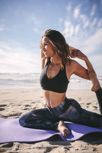 Happy woman doing yoga exercise on beach