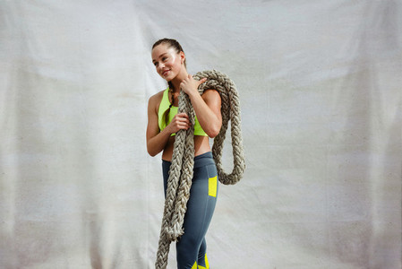 Female athlete with battle rope on white background