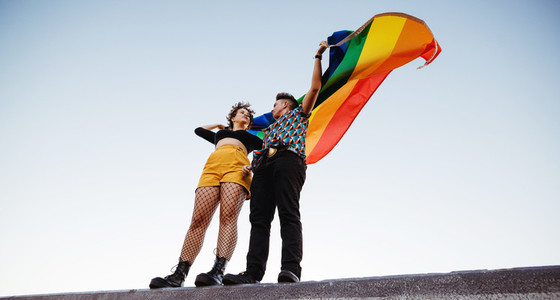 LGBTQ couple raising the rainbow pride flag