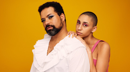 Drag queen with androgynous woman on yellow background