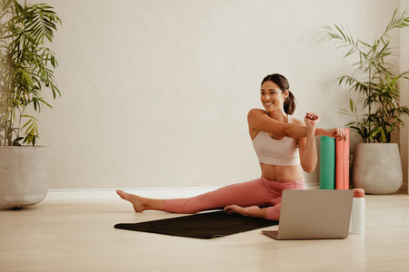 Woman stretching watching online video on laptop