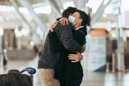 Woman welcoming man at airport post pandemic