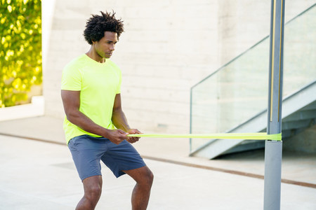 Black man working out with elastic band outdoors