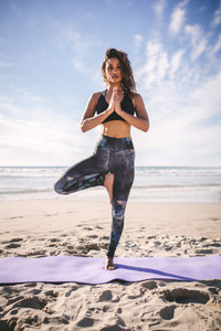 Fitness woman meditating on beach