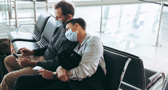 Passenger couple wearing face masks waiting for delayed flight