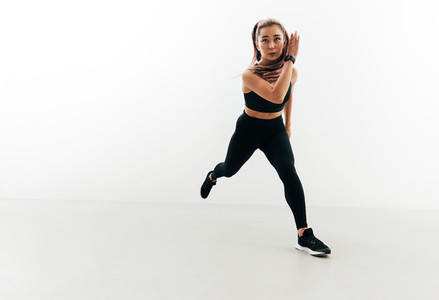 Muscular woman exercising in studio  Young female running forward