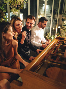 Cheerful woman singing while her friends play the piano