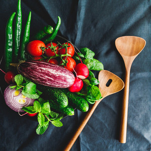 Various fresh colorful vegetables in a plate on a table with wooden kitchen utensils  Top view