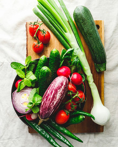 Various fresh colorful vegetables in a plate on a table with wooden kitchen utensils  Top view