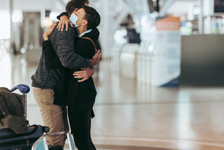 Woman receiving man at airport arrival after pandemic