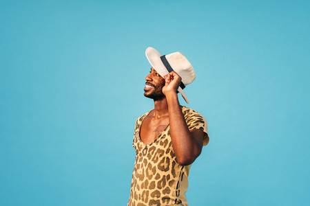 Young guy posing against a blue background  Stylish male with a straw hat