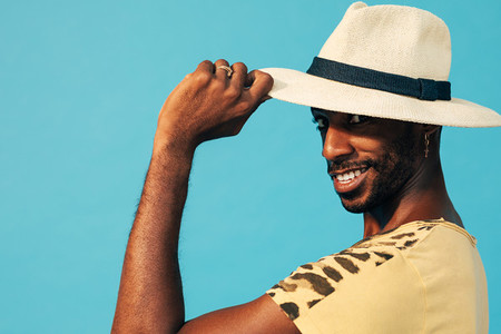 Portrait of a happy man wearing a straw hat looking at camera against a blue background