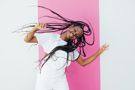 Young happy woman with long hair having fun against white wall with pink stripe