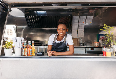 Portrait of young saleswoman waiting for clients Food truck owner leaning on a counter looking away