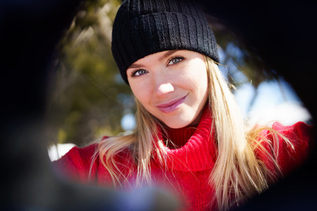 Young blonde woman taking a selfie in a snowy mountain forest in winter