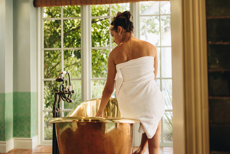 Young woman preparing a luxury bath in a hotel