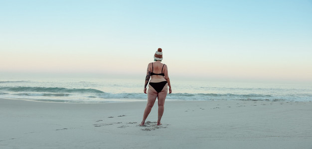 Anonymous female winter bather standing at the beach